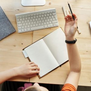 Teen girl actively learning in an organized home workspace via online class on a desktop computer.
